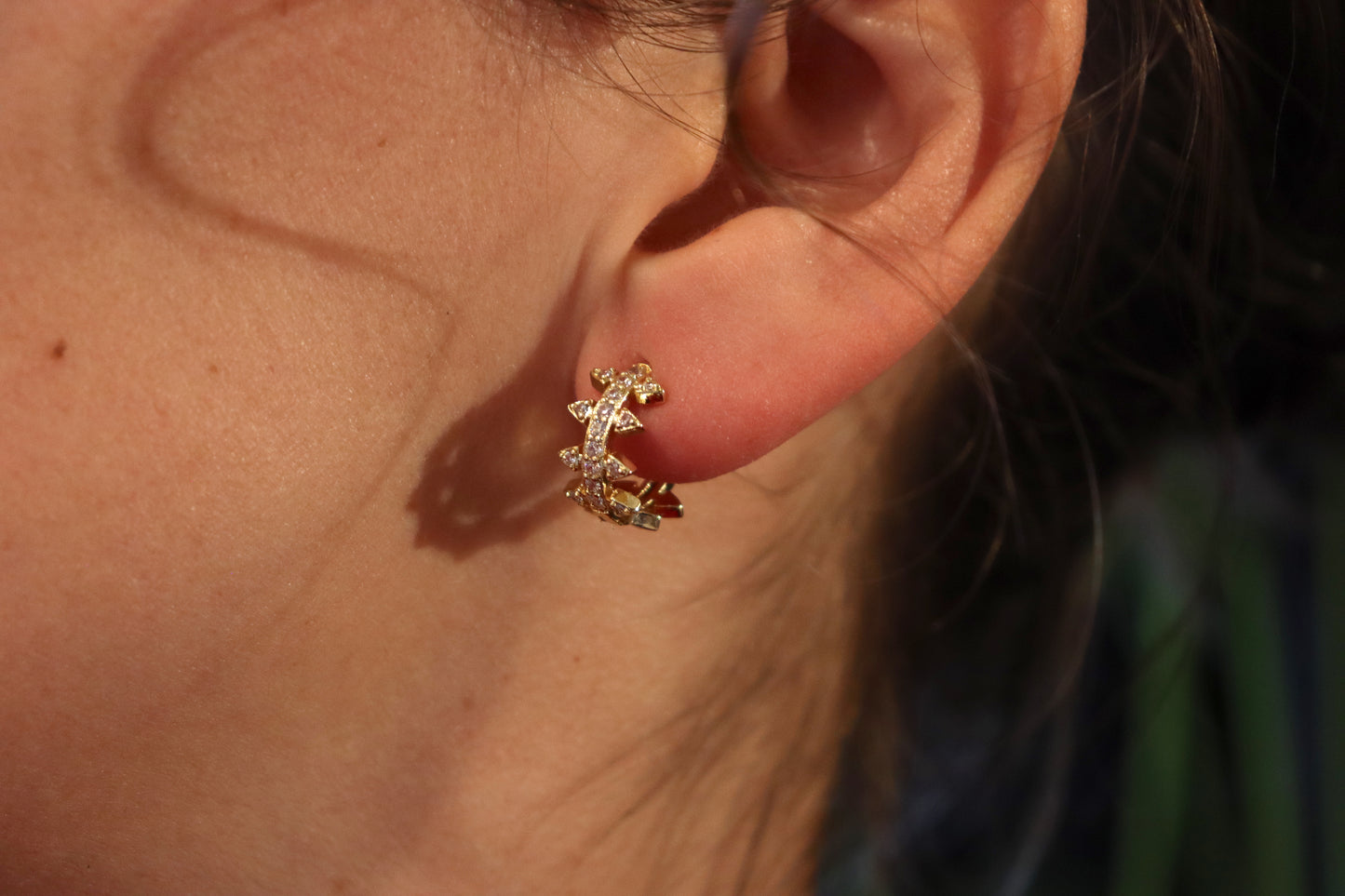 Brass Huggie Earrings With Cubic Zirconi & Spikes. Small hoop earrings with spikes worn on an ear.