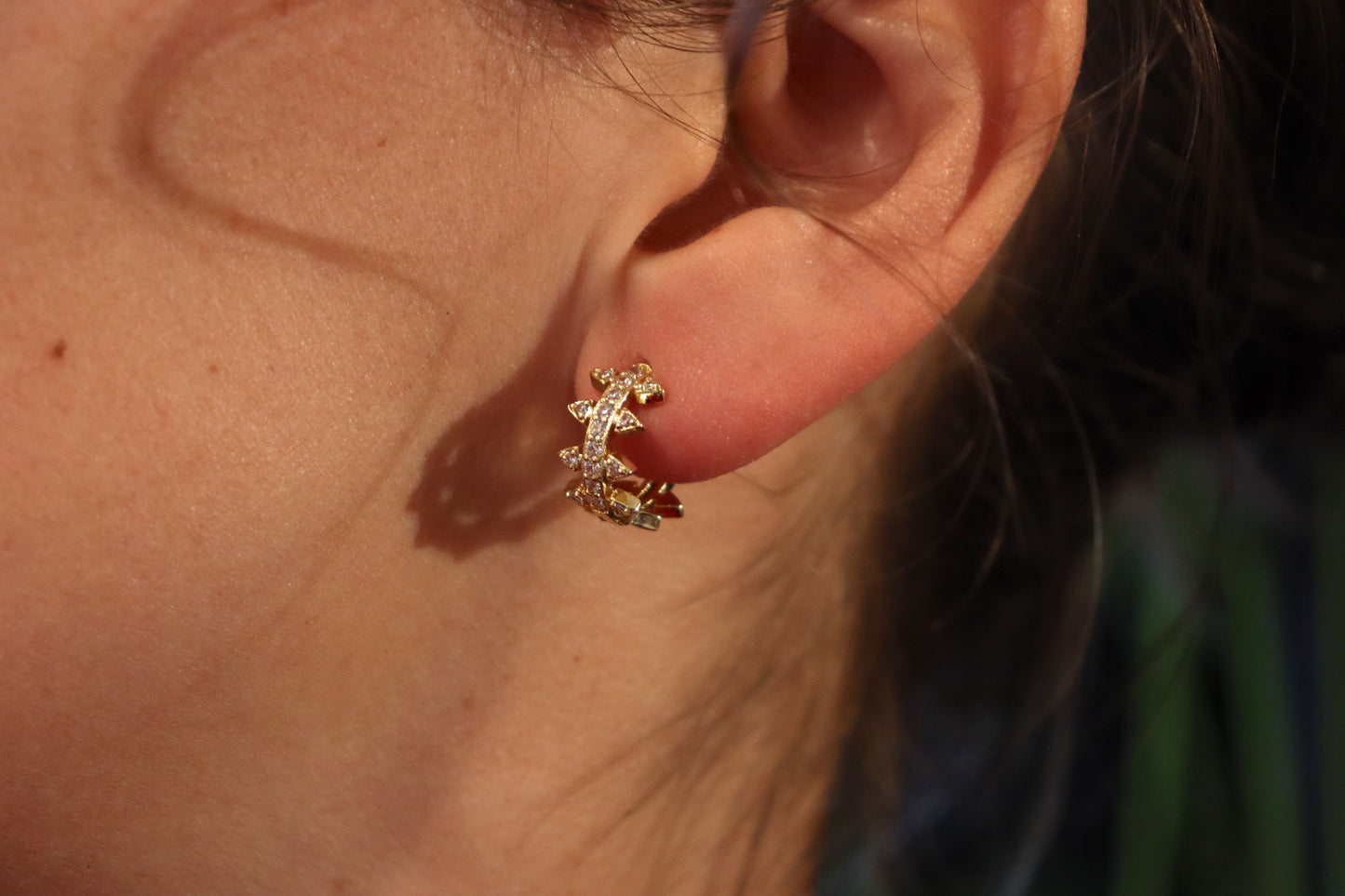 Brass Huggie Earrings With Cubic Zirconi & Spikes. Small hoop earrings with spikes worn on an ear. 
