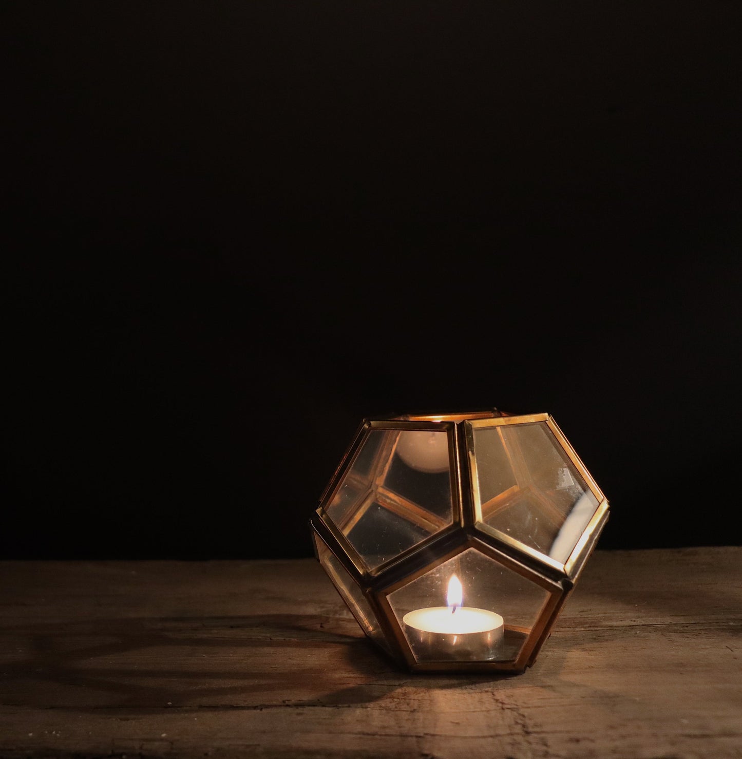 A beautiful candle holder in a hexagon design, with glass and brass that has been welded by hand. A lantern for any room.